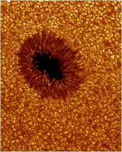 Foto del granulado de la Fotosfera Solar, junto a una de las llamadas manchas solares, que son focos de emisión de luz en alta frecuencia: “el Sol nace diariamente de pequeñas porciones de fuego aglomeradas” (Jenófanes). Estos gránulos tienen un tamaño de unos mil kilómetros y una vida media de 20 minutos